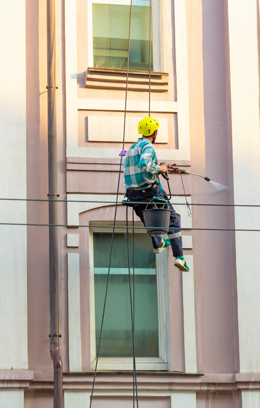 Man cleaning windows and wall on old city bulding.